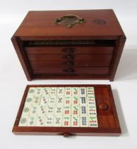 Bone and wood mahjong set with instruction booklet, in stained wood five-drawer table top cabinet
