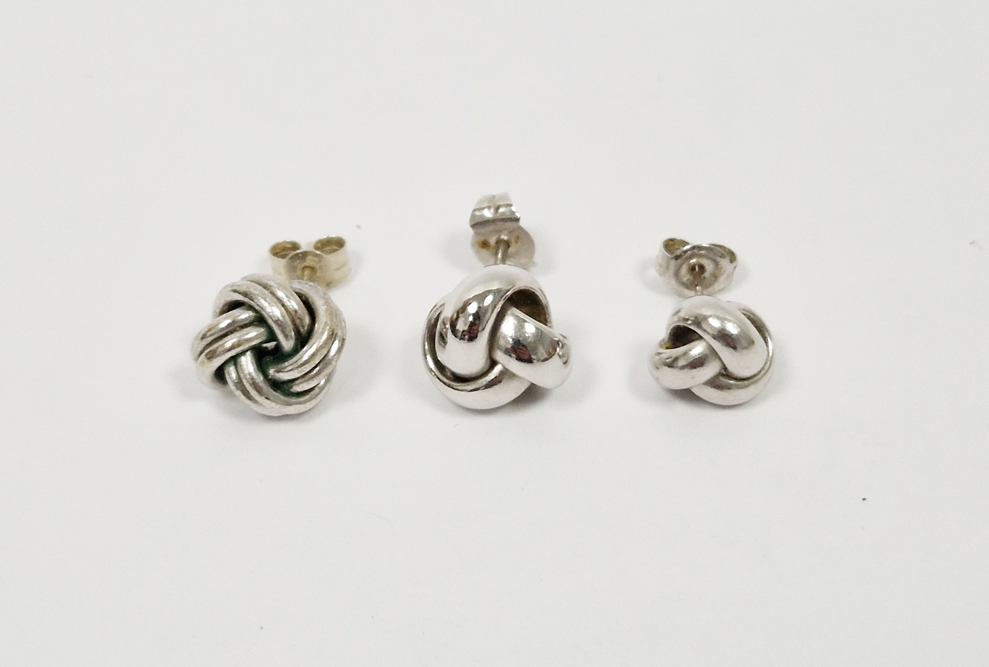 Two 9ct white gold knot-pattern earrings and another white metal knot-pattern earring, 2.6g total