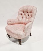 Victorian buttonback armchair upholstered in a pink and cream floral pattern fabric and raised on