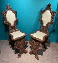A Pair Of Continental Sgabello Chairs, Heavily Carved With Grotesques And Cherubs.