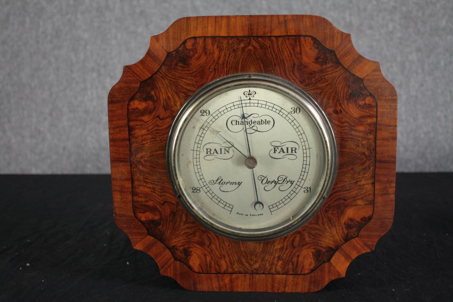 An early to mid twentieth century barometer made in England. In a walnut veneer case. .H.30 W.30cm.