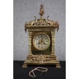 A 19th century ornate Classical design brass mantle clock with putti finial. Silvered dial with