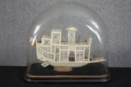 A Chinese flower boat. Nineteenth century and made from bone. Housed in glass dome. Highly