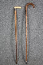 A pair of walking canes. The smaller one with a bone and silver handle the other, German and