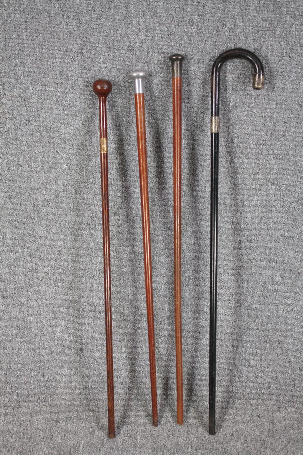 A collection of four walking canes. The darker stick with a silver collar and end. L.92cm. (longest)