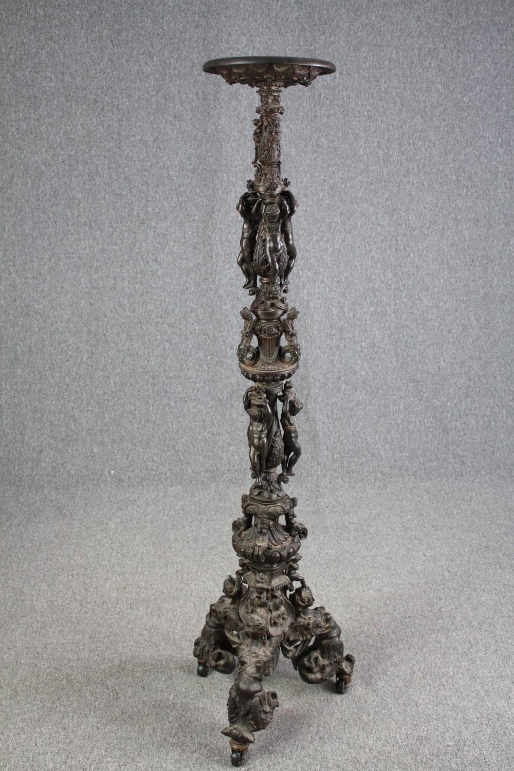 A large bronze 19th century Classical style figural torchere decorated with putti holding the