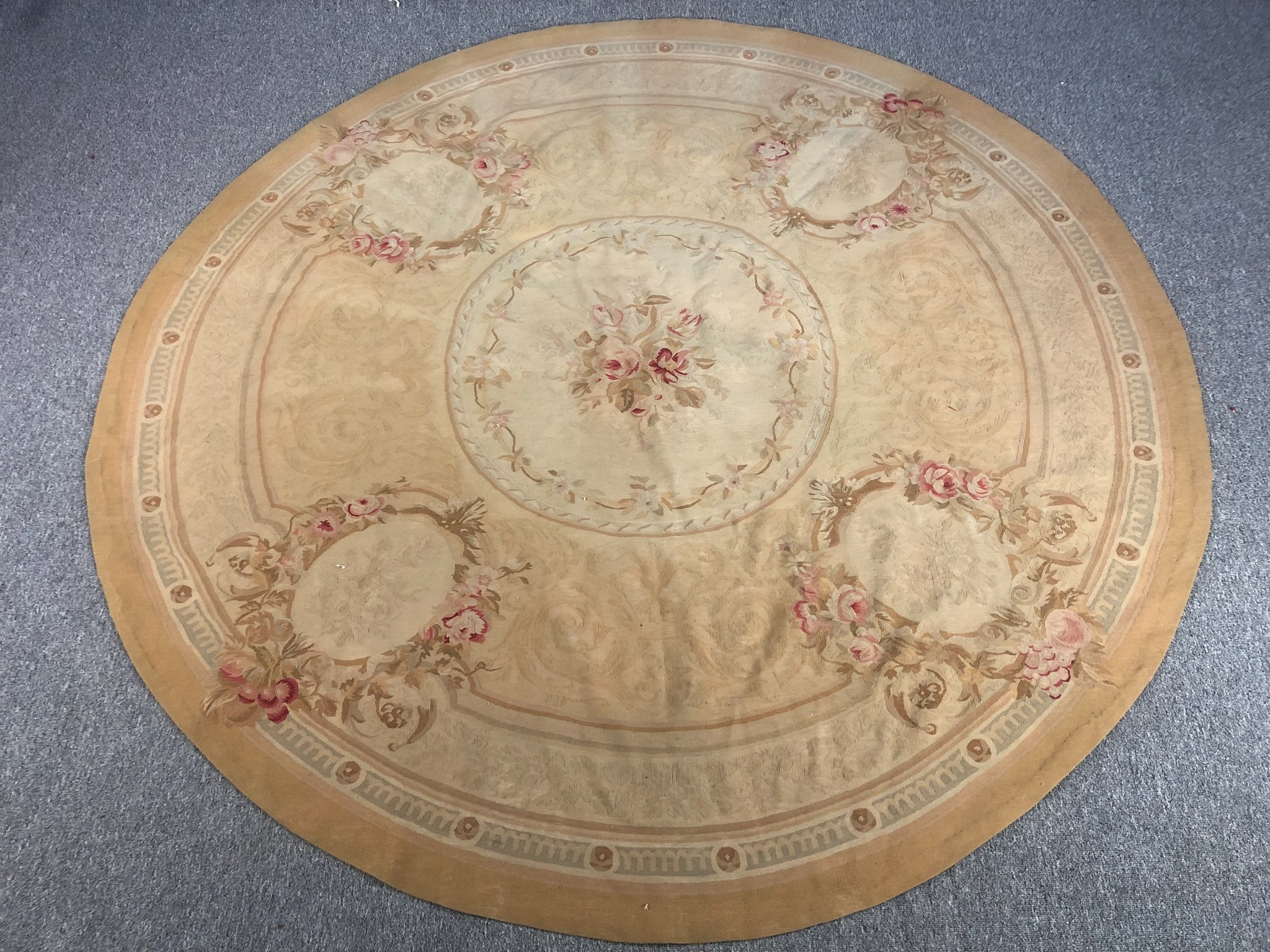 A hand woven Aubusson style rug with floral spray medallions on a beige ground. Dia.240cm.