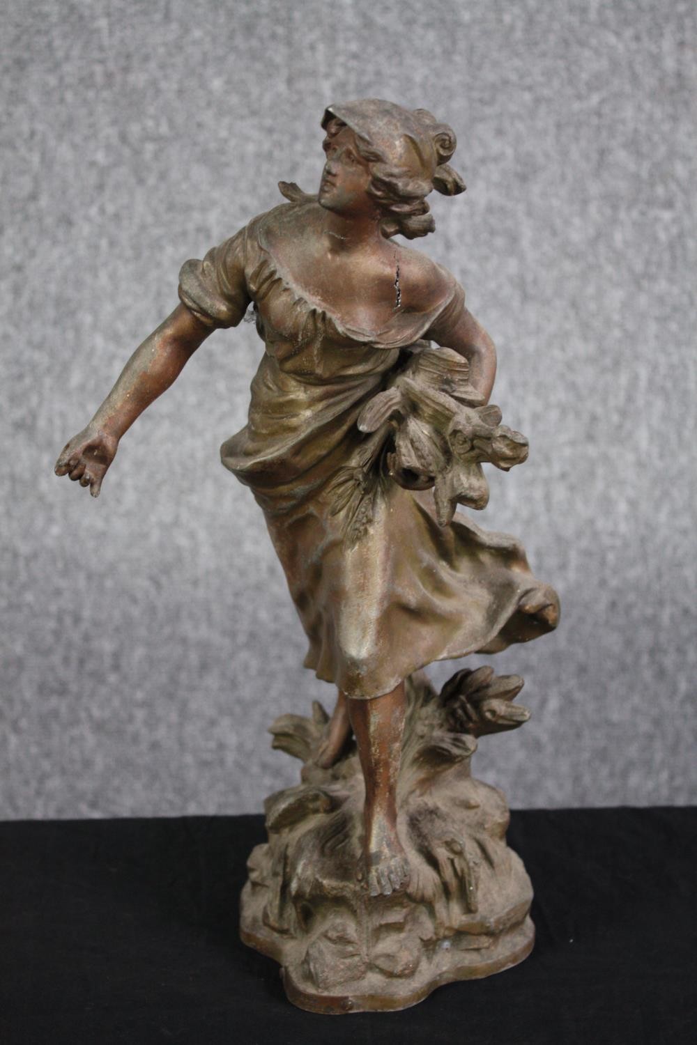 A metal figure. Probably early twentieth century. A women sowing seeds. With some damage to the