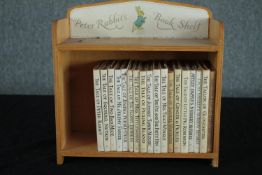A collection of late editions of Beatrix Potter books housed in a bookshelf. H.28 W.28 D.12cm.