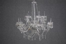 A crystal chandelier with eleven branches of lights. H.70cm. (In need of some repair).