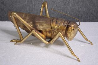 A decorative grasshopper, gold lacquered. H.5 W.39cm.