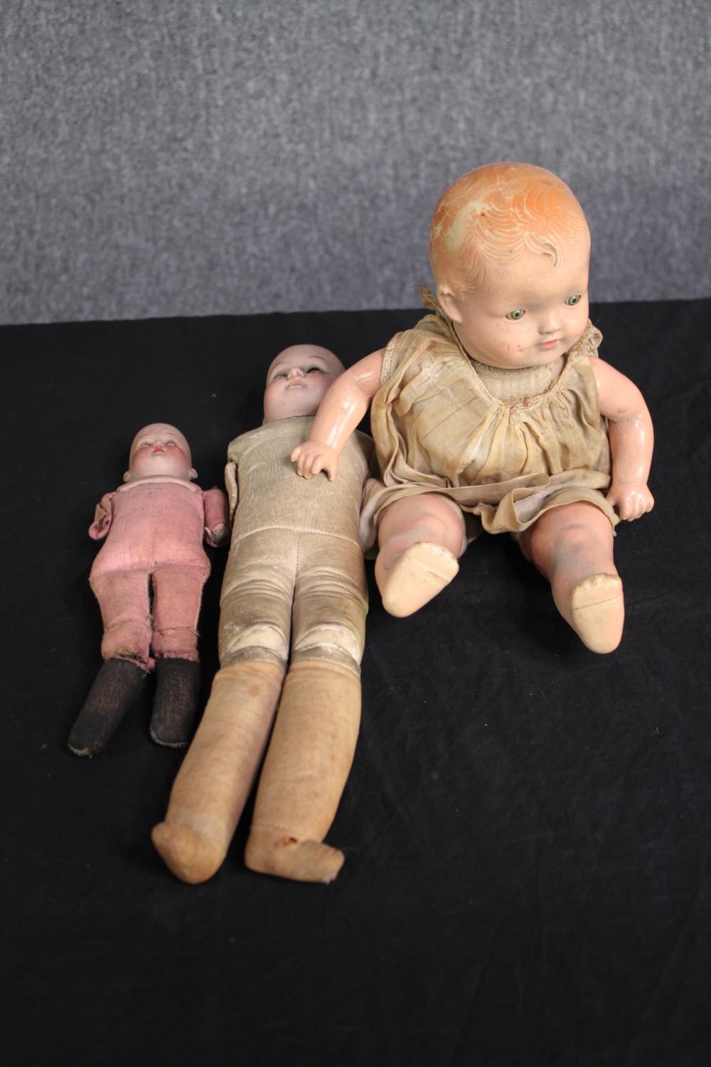 A collection of three dolls. With glass eyes. Two incomplete and missing arms. L.37cm. (largest)