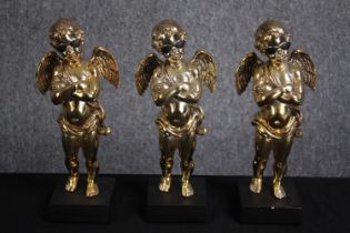 Three matching cherub figures wearing sunglasses and finished in gold. H.28cm.(each)