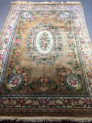 A large woollen Aubusson style carpet with a central flowerhead medallion on an ochre field within
