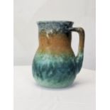 A Ruskin jug glazed in bands of blue, ochre and green, stamped to base. H.16 W.13 D.13cm.