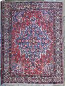 Carpet, hand knotted Persian with central sapphire flowerhead medallion on a madder ground within