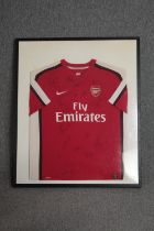 A framed Arsenal football shirt. Signed by, among others, Theo Walcott, Song, and Ramsey. The