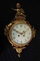 A Rococo cartel style gilt metal clock mounted with a cherub. H.46 W.27cm.