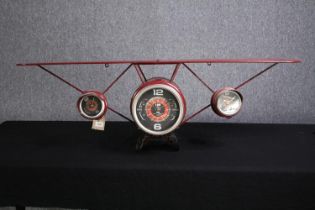 A wall mounted clock. The clock face in the style of aircraft instrument dials. H.40 W.124cm.