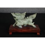 A Chinese carved hardstone mythical animal on hardwood display stand. H.12 W.18 D.9cm.