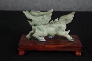 A Chinese carved hardstone mythical animal on hardwood display stand. H.12 W.18 D.9cm.