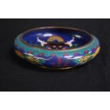 An antique Chinese cloisonné shallow bowl decorated with a dragon. Enamelled in bright blues, yellow