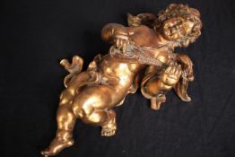 A plaster cherub playing a lute. Plaster finished in gold lacquer. H.50cm.