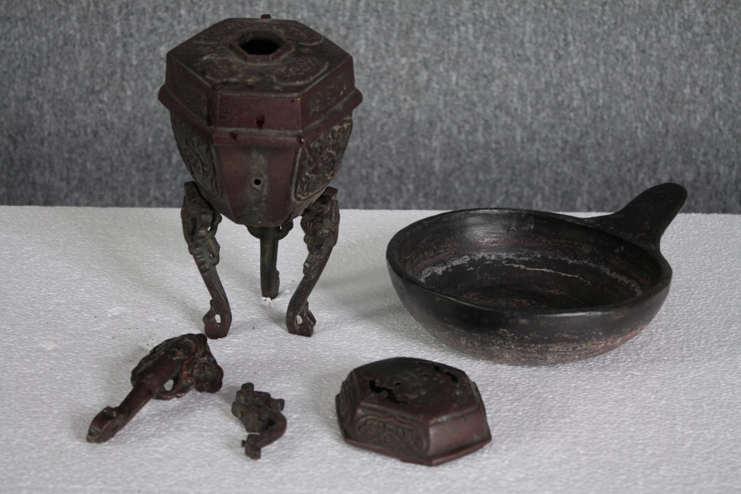 An mixed collection of iron and bronze metalware. Includes a pot on a stand with one leg detached