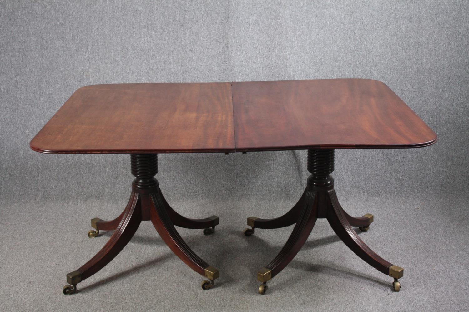 A George III mahogany twin pedestal dining table on quadruped swept supports terminating in brass