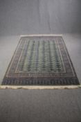Carpet, woollen Bokhara style with repeating gul motifs on a sage ground. L.230 W.151cm.