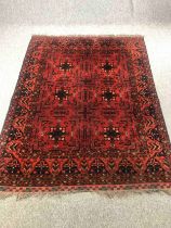 A Kazak carpet with repeating star medallions on a burgundy ground within stylised multiple borders.
