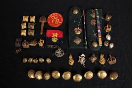 A mixed collection of military brass buttons, badges, epaulettes and medal ribbons. Includes a badge