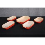 A collection of four Le Creuset baking dishes in the classic orange finish. L.31 W.28cm. (largest)