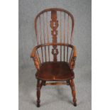 An early 19th century elm seated Windsor armchair with hooped back and pierced splat on turned