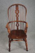 An early 19th century elm seated Windsor armchair with hooped back and pierced splat on turned