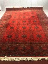 A large Eastern carpet with stylised foliate motifs across the burgundy field within multiple floral