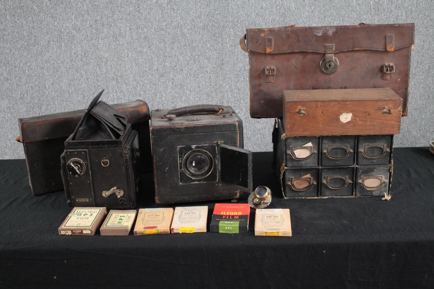 A collection of vintage plate cameras and accessories. Includes a Cooke Anastomosis lens, cases, and