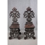 A pair of 19th century Italian carved oak Sgabello chairs. H.121cm. (Some carving missing as seen).