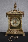 A 19th century ornate Classical design brass mantle clock with putti finial. Silvered dial with