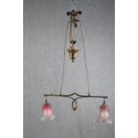 A 1920's Art Nouveau adjustable brass ceiling lamp. Two lights shaded in frosted cranberry glass