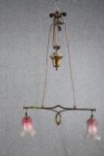 A 1920's Art Nouveau adjustable brass ceiling lamp. Two lights shaded in frosted cranberry glass