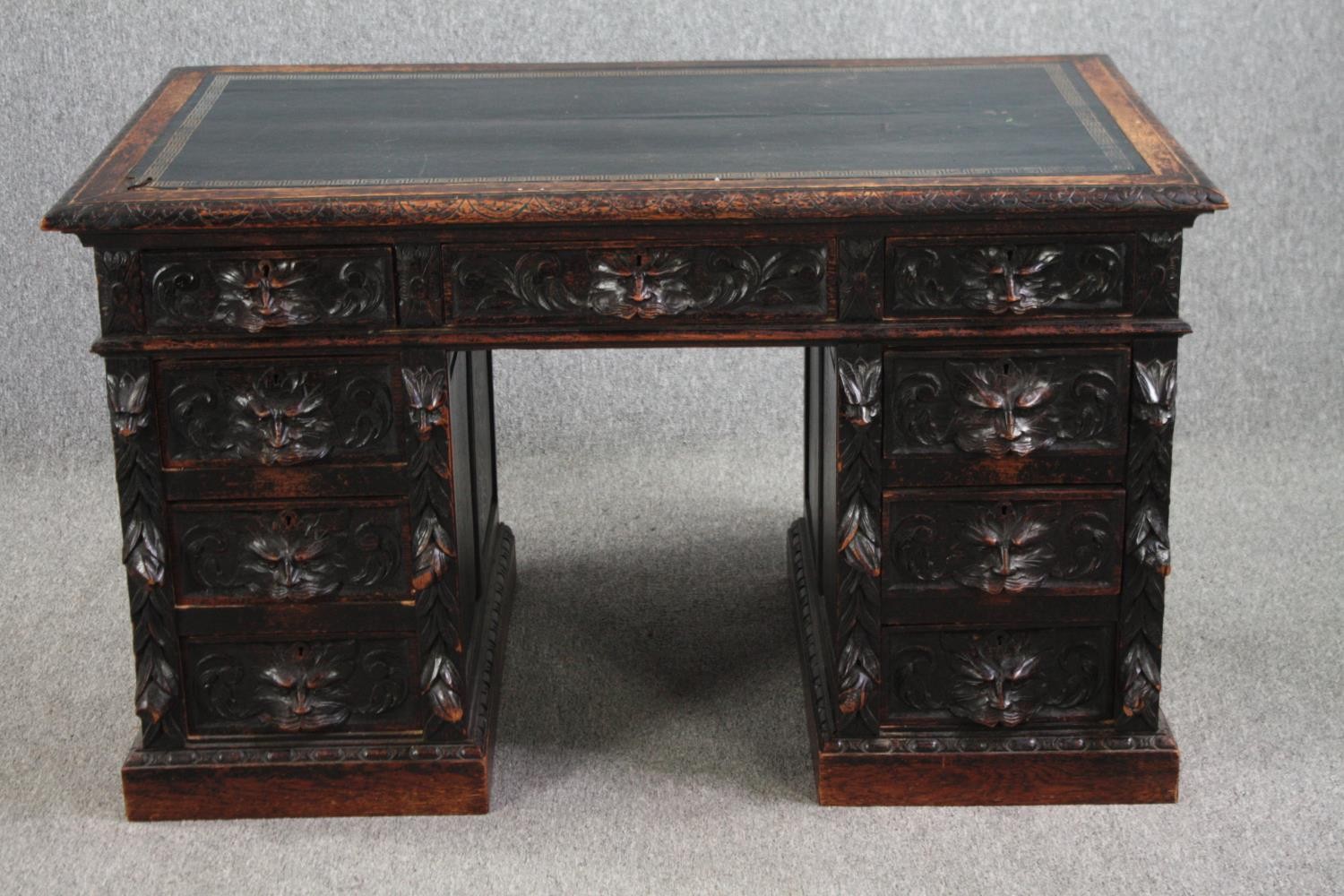 Pedestal desk, late 19th century carved oak with Green Man mask handles and tooled leather inset