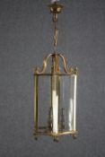 A brass pendant ceiling light holding three bulb fittings. A couple of glass panes are missing.