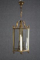 A brass pendant ceiling light holding three bulb fittings. A couple of glass panes are missing.