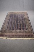 Carpet, woollen Bokhara style with repeating gul motifs on a sapphire ground. L.225 W.149cm.