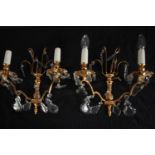 A pair of brass wall lights each with two arms of lights and crystal drop detailing. H.28cm. (each)