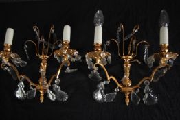 A pair of brass wall lights each with two arms of lights and crystal drop detailing. H.28cm. (each)