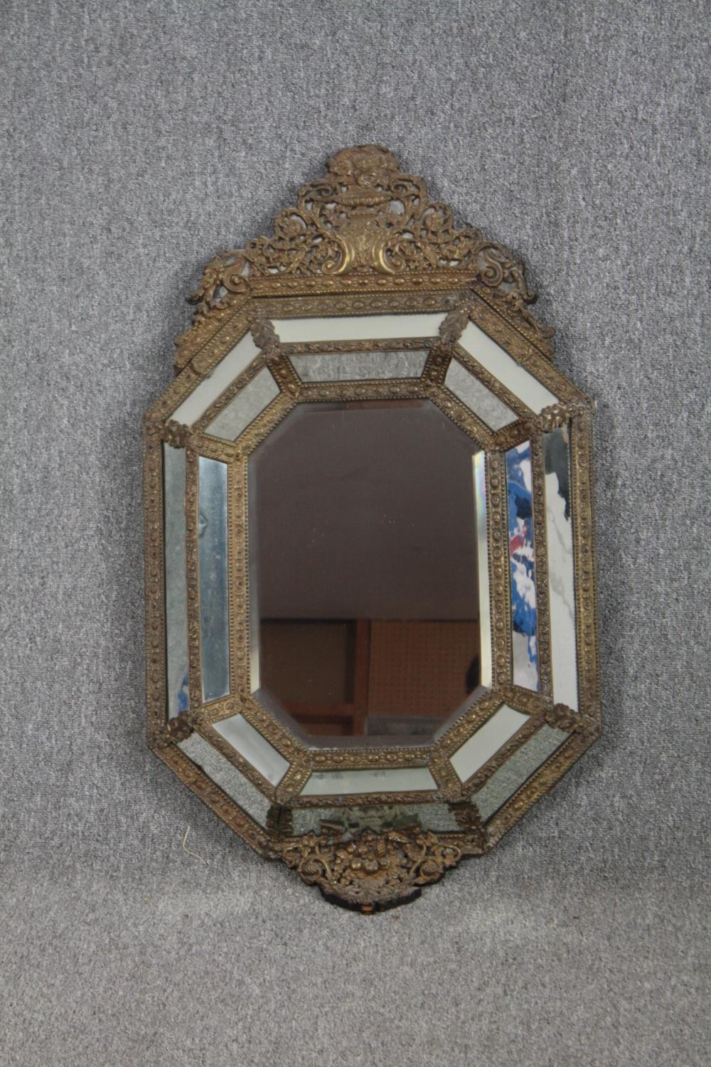 Wall mirror, C.1900 Dutch style in repousse metal cushion frame. H.109 W.62cm.