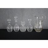 A mixed collection of four glass decanters and a jug. Cut glass and complete with their stoppers.