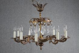 A French foliate design chandelier with ten brass branches and decorated with hanging teardrop glass